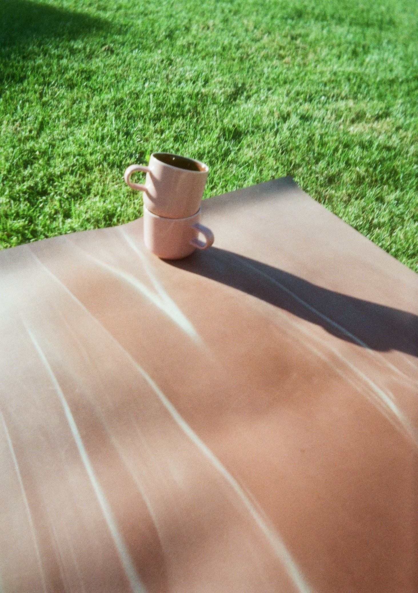 Two mugs on a mat in the grass